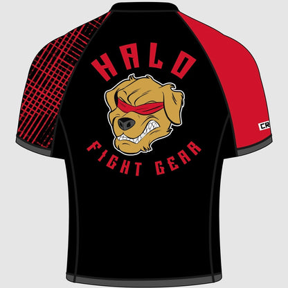 The image shows the back of a short-sleeved rash guard. The main body is black, with the right sleeve featuring a black and red criss cross pattern, and the left sleeve being solid red. In the center of the back, the Halo Fight Gear logo is displayed, showing a fierce golden retriever with bared teeth and wearing a red blindfold. Above the dog's head, "HALO" is written in bold red letters, and "FIGHT GEAR" appears below in matching red text.